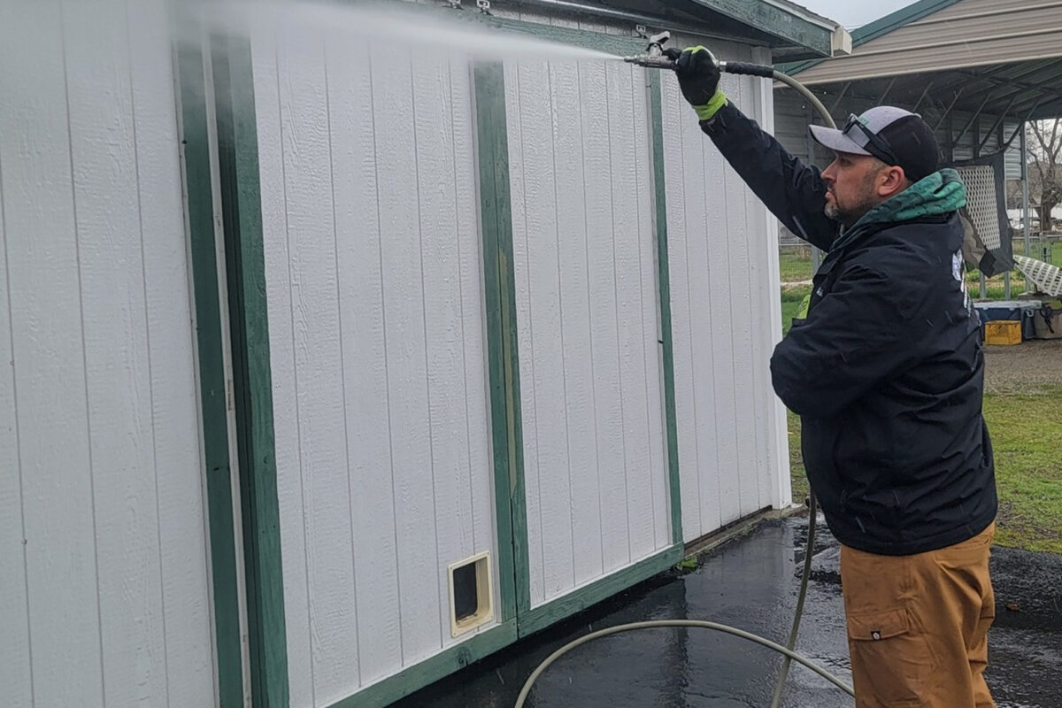 Soft washing and pressure washing of an exterior outbuilding on a residential property in Hauser, ID, cleaning the siding and removing buildup.